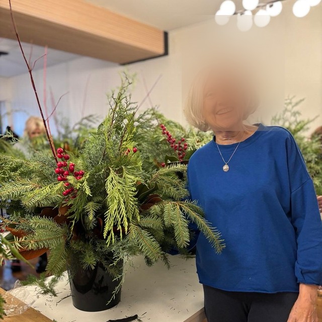 A Buff Muff member at home beside an arrangement of greenery, face obscured
