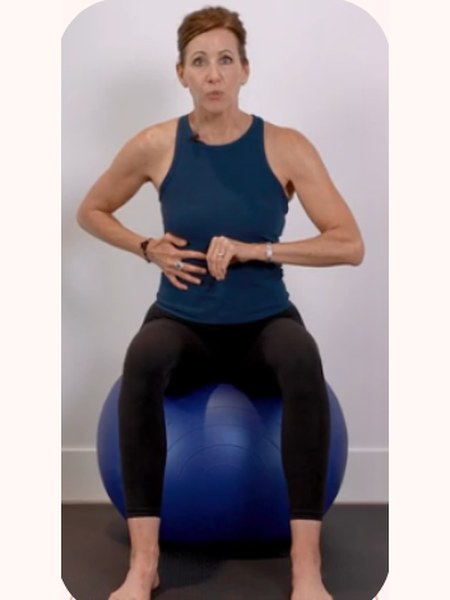 Seated on an exercise ball, hands at the waist, practising a foundational breath