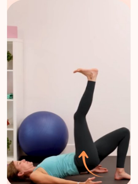 Lying with one leg raised beside an exercise ball, reinforcing automatic pelvic protection